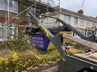 A skip being lifted off the lorry outside a house