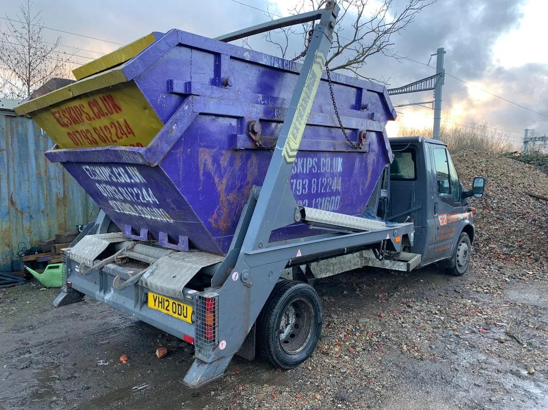 A purple EZSKIPS skip loaded on the back of a skip lorry
